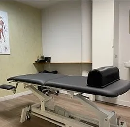 Behandelruimte met een massagetafel en een anatomieposter